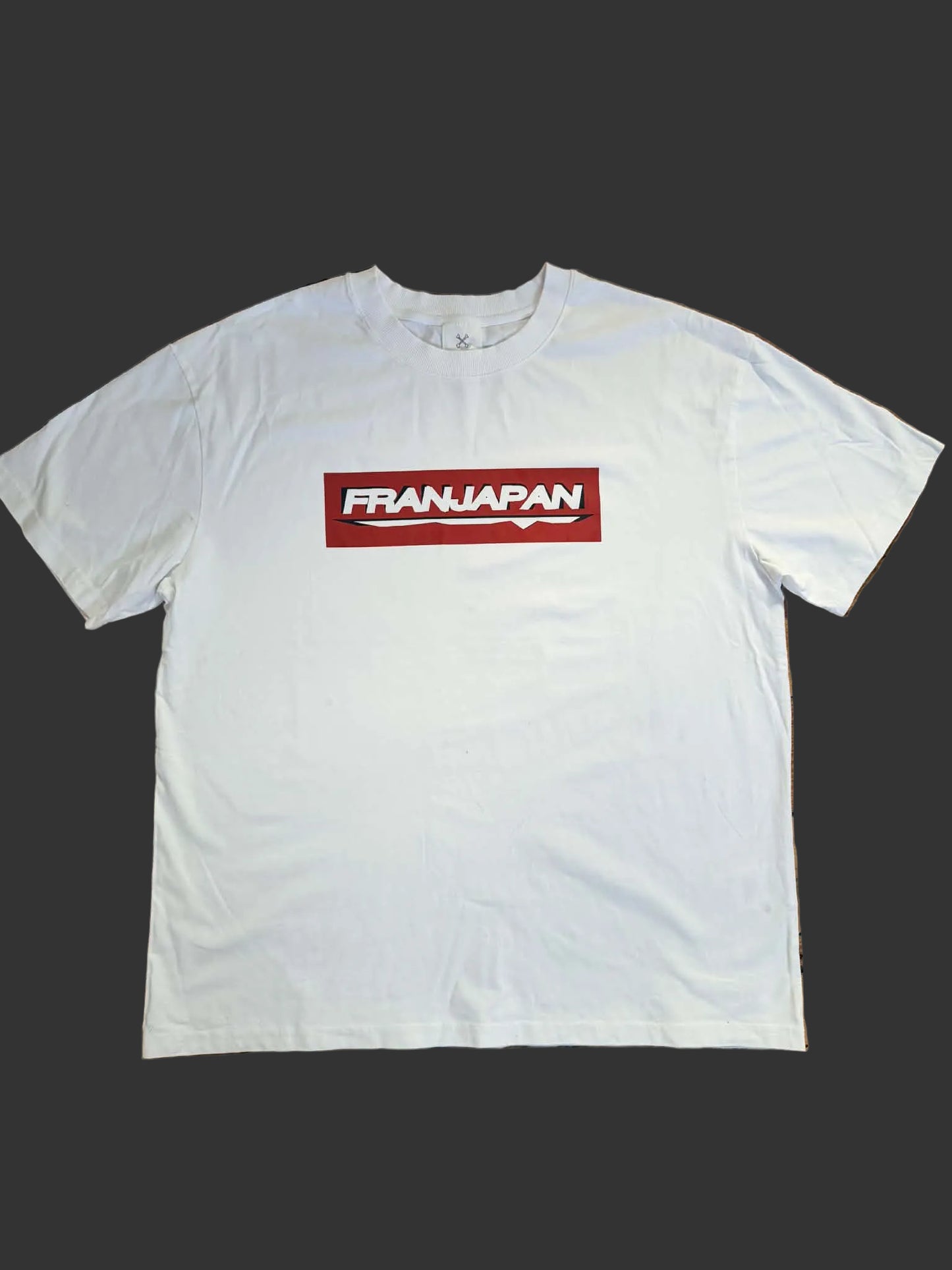 White t-shirt with a red and black logo on a wooden floor